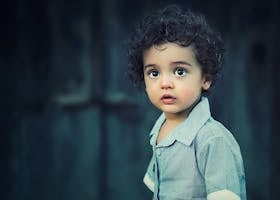 Charming portrait of a young boy with curly hair and striking eyes.